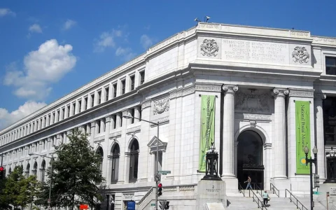White stone facade of the Postal Square Building in Washington, D.C., with green National Postal Museum banners.