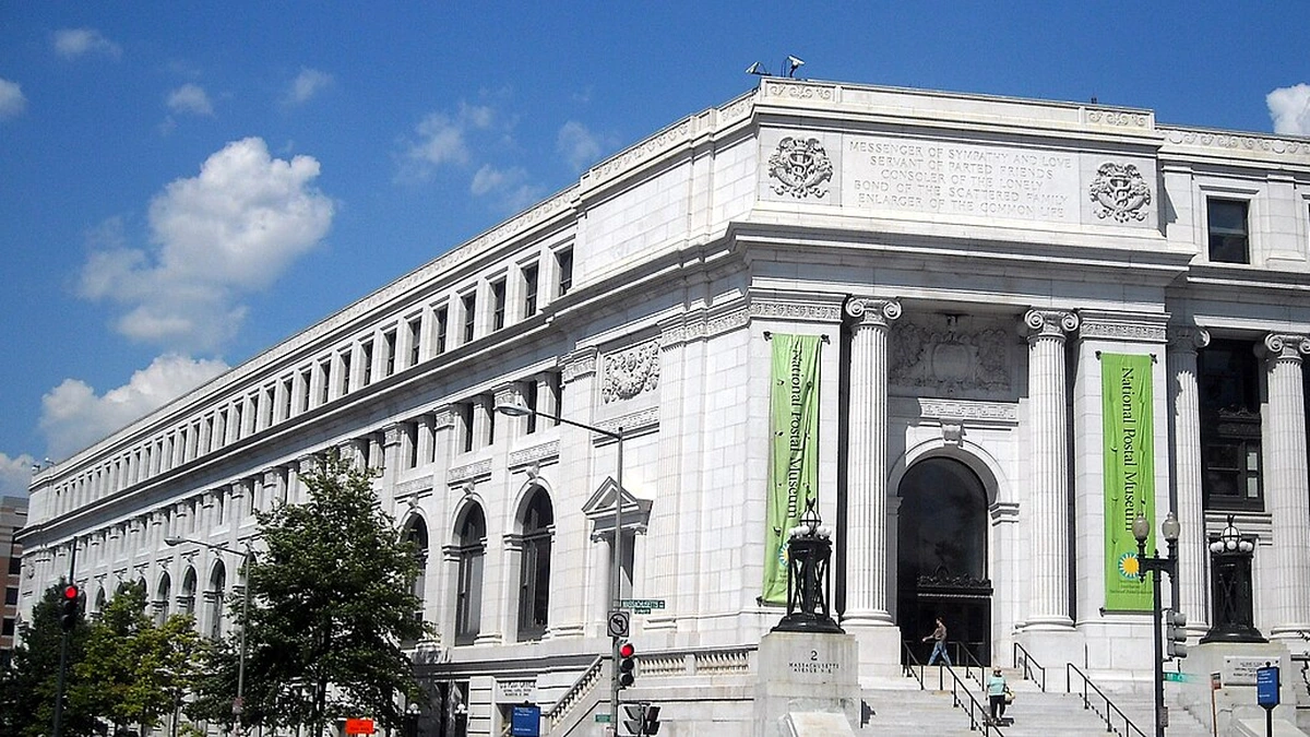 White stone facade of the Postal Square Building in Washington, D.C., with green National Postal Museum banners.