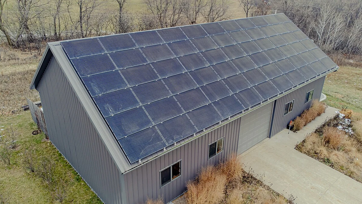 Aerial view of a metal-roofed building covered with photovoltaic solar panels.