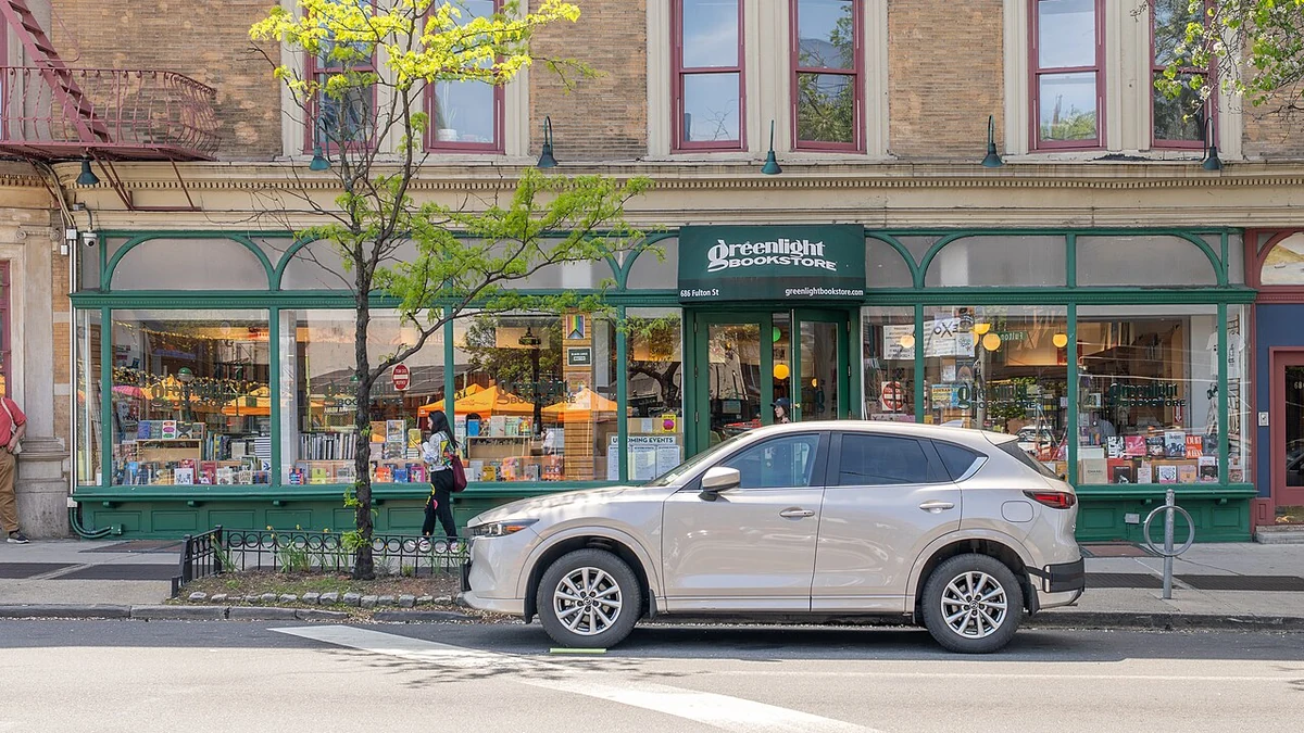 Exterior of Greenlight Bookstore in Brooklyn, with books visible in the front windows and a vehicle parked outside.