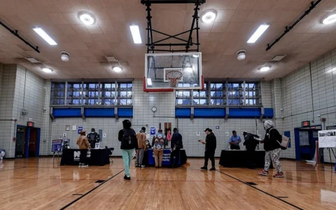 Job seekers speaking with recruiters at an MTA job fair held in a gymnasium in East Harlem, New York.