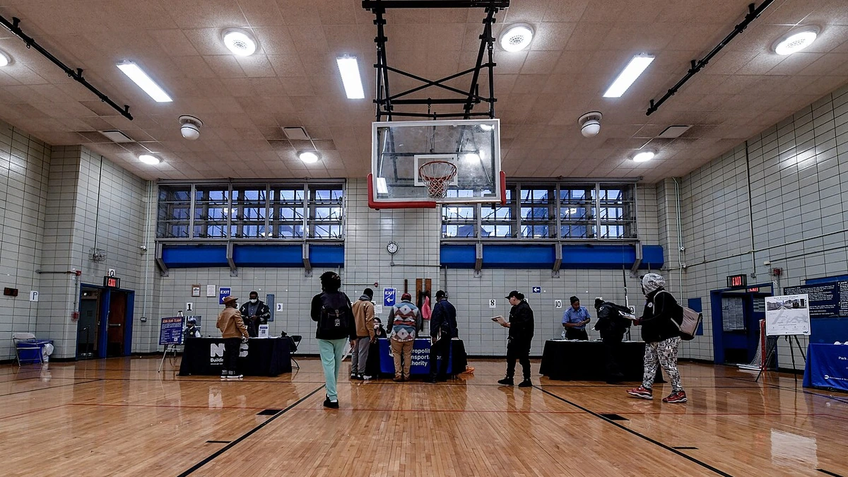 Job seekers speaking with recruiters at an MTA job fair held in a gymnasium in East Harlem, New York.
