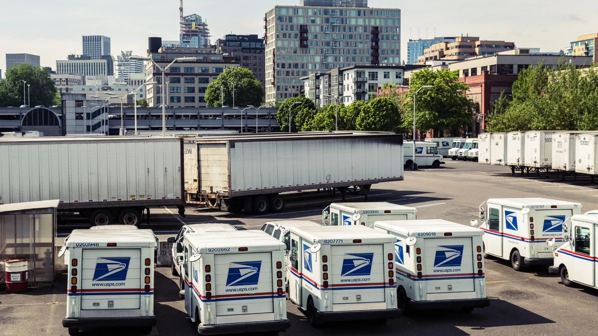 USPS delivery trucks and mail trailers parked at the Portland Main Post Office distribution facility in Oregon.