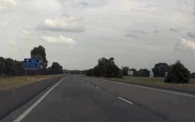 The southbound Hume Freeway near Byawatha, Victoria, with a blue rest-area sign beside the road.