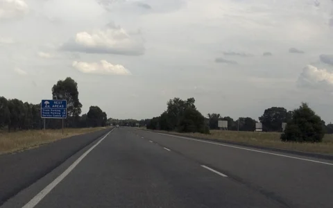 The southbound Hume Freeway near Byawatha, Victoria, with a blue rest-area sign beside the road.