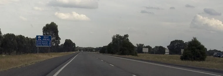 The southbound Hume Freeway near Byawatha, Victoria, with a blue rest-area sign beside the road.