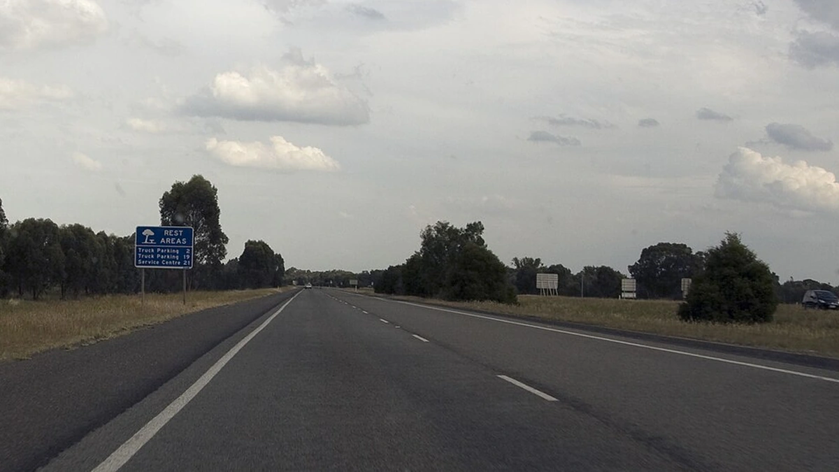 The southbound Hume Freeway near Byawatha, Victoria, with a blue rest-area sign beside the road.
