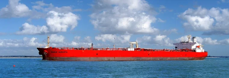 Red-hulled Eagle Augusta crude-oil tanker passing through waters near the Houston Ship Channel under a cloud-filled sky.