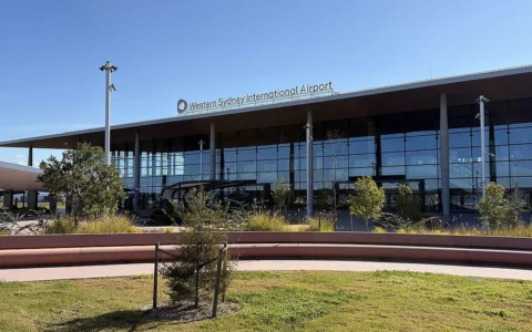 Glass-fronted Western Sydney International Airport passenger terminal with the airport name above the entrance.